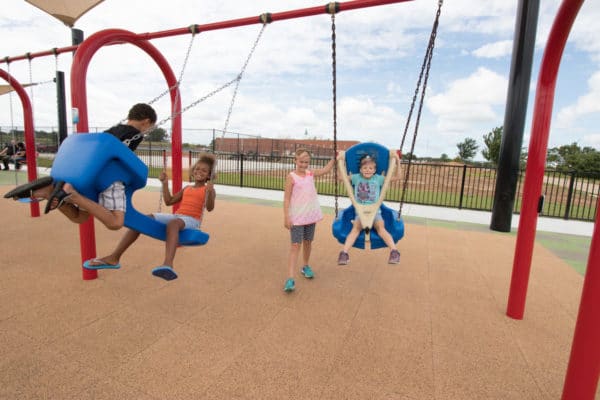 Kids playing on an accessible swing.
