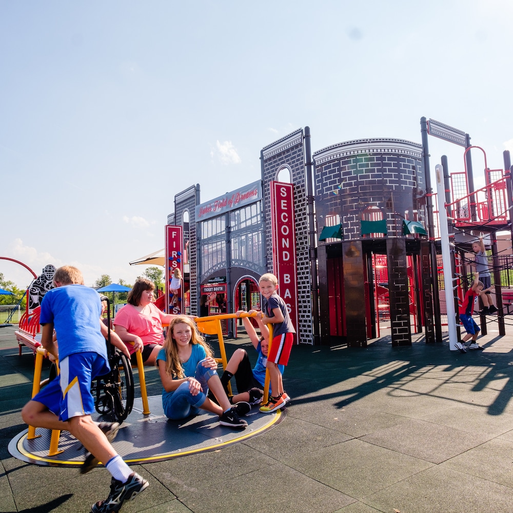 Children with different abilities play together on a baseball themed inclusive playground.