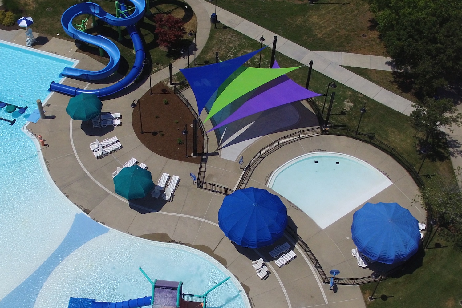 Blue, green and purple triangular shade sails overlap each other at a water park.