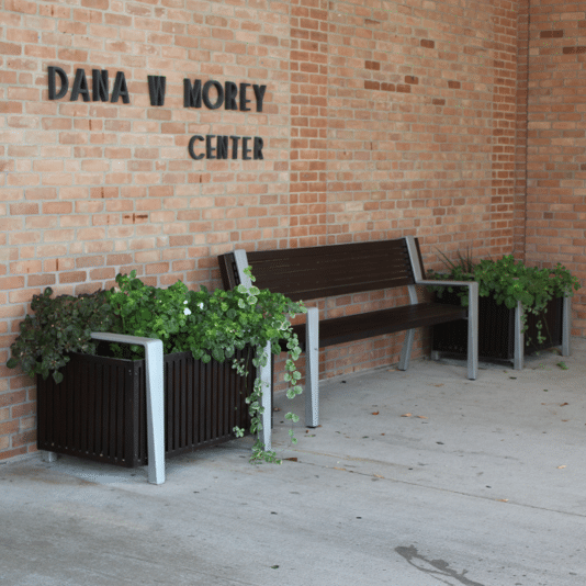 Commercial flower planters and a bench outside a community center.