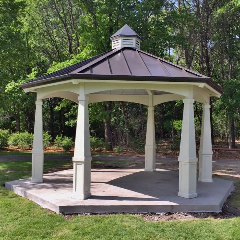 A gazebo with white pillars and gray roof in a park setting.