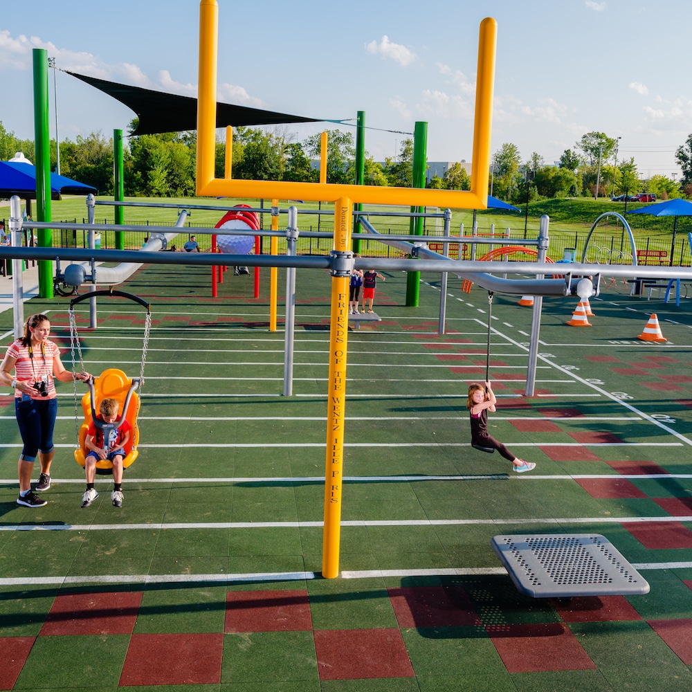 Children and parents play on a sports themed zipline.